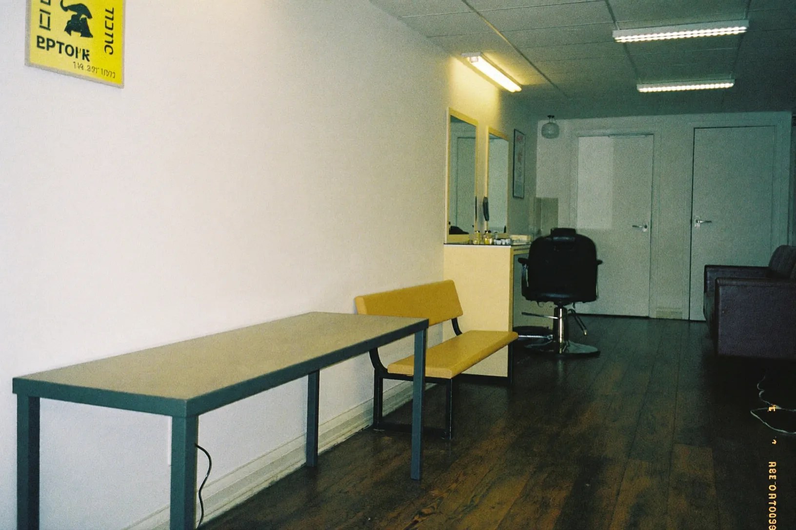 An empty styling chair in front of the mirror, waiting seats beyond